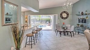 A spacious dining area with a large window, a chandelier, and a clock on the wall. - Modern House < 5 Miles to Port Charlotte Beach! (Port Charlotte)