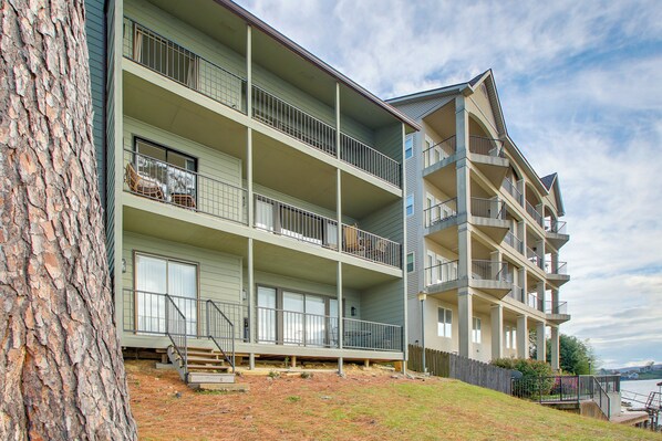 A multi-story residential building with balconies, a wooden deck, and a view of the water.