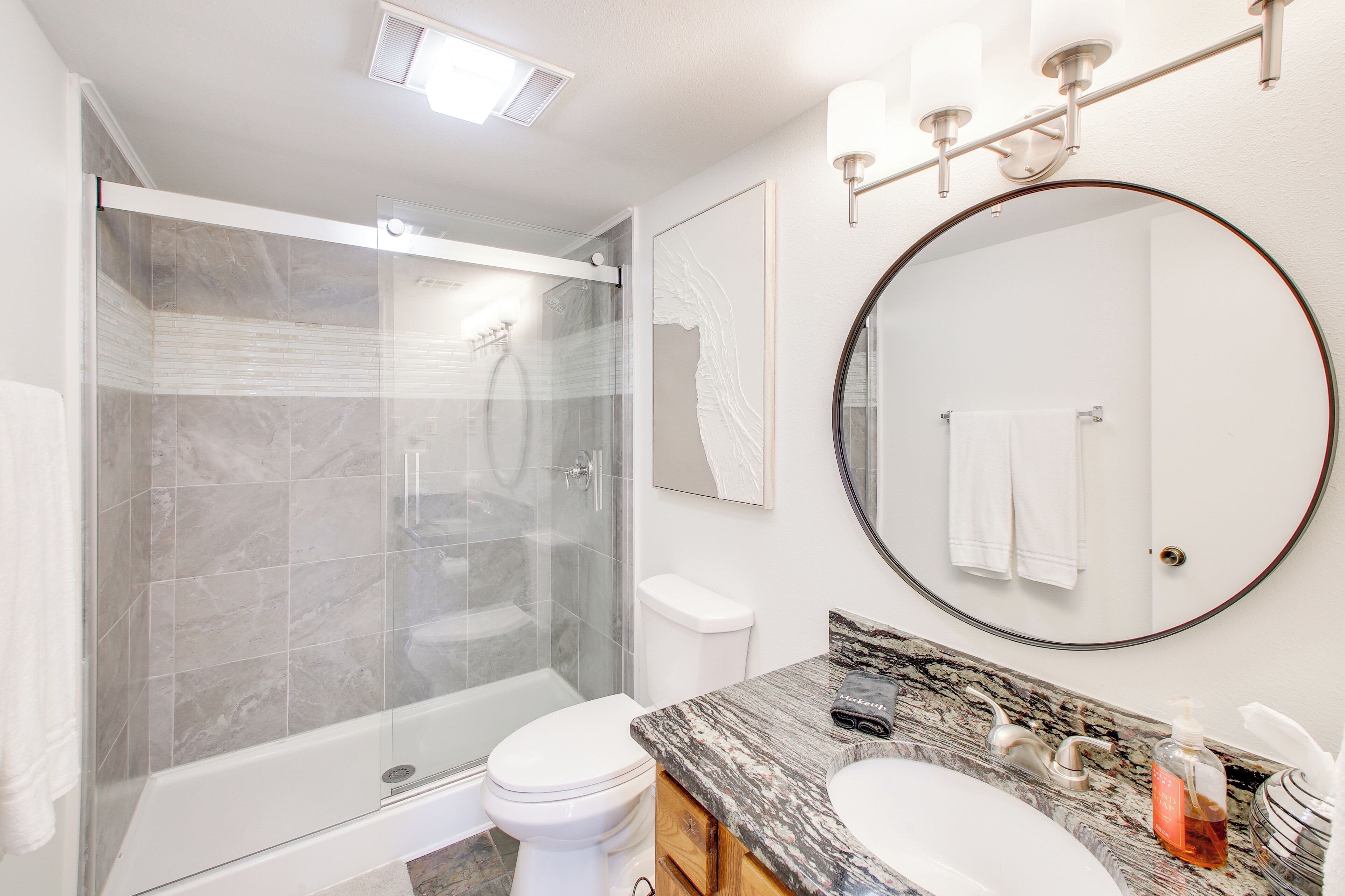 Une salle de bain moderne avec une douche à parois de verre, des toilettes, un lavabo et un grand miroir.