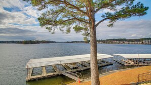 A lakeside dock with covered seating areas and a tree in the foreground. - Sunset-view Resort Condo on Lake Hamilton! (Hot Springs)