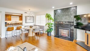 A modern kitchen with wooden cabinets, a dining area with a round table and chairs, a fireplace, and a large potted plant. - Sunset-view Resort Condo on Lake Hamilton! (Hot Springs)