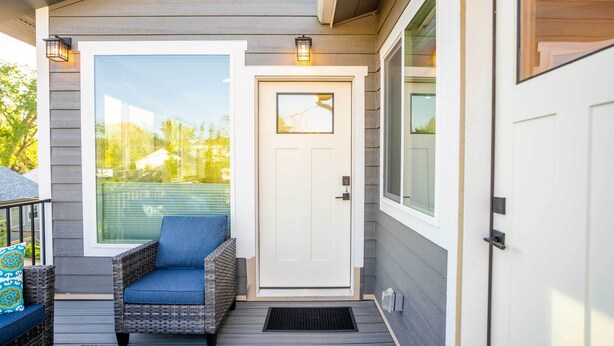 A front porch with a wicker chair, a white door, and a large window. - Golden Cottage Near Red Rocks & School of Mines! (Golden)