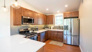 A modern kitchen with wooden cabinets, stainless steel appliances, and pendant lighting. - Golden Cottage Near Red Rocks & School of Mines! (Golden)