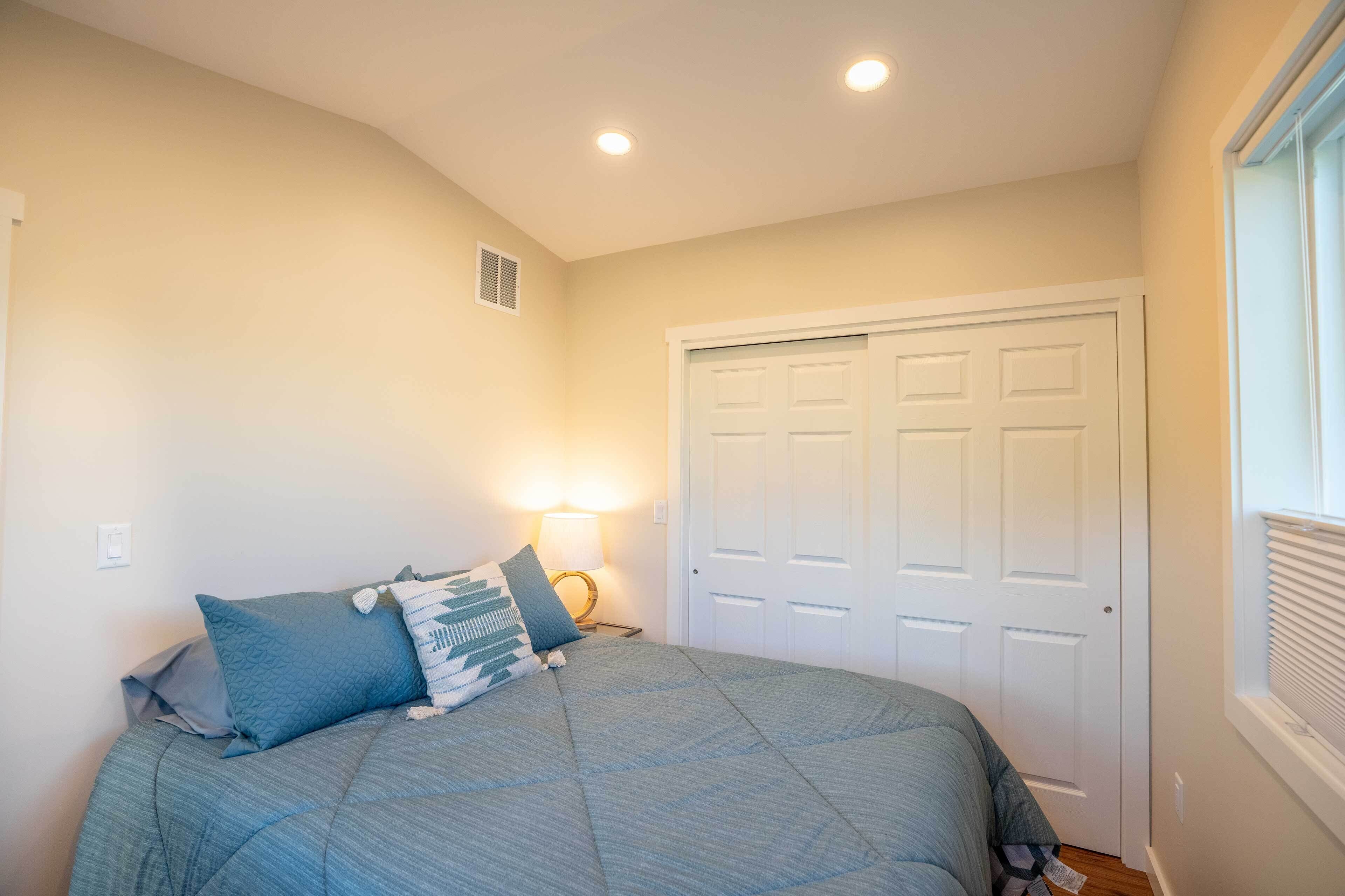 A bedroom with a bed, a nightstand, a lamp, and a closet.