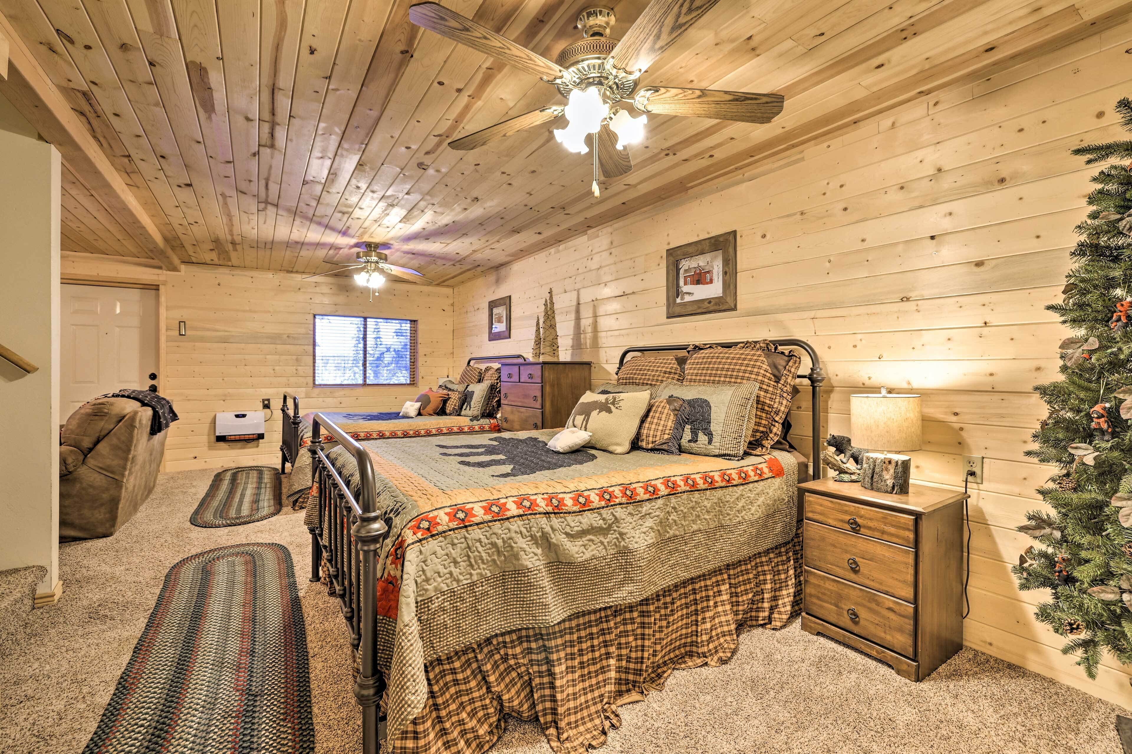 Un dormitorio acogedor con techo de madera, cama con colcha escocesa, mesita de noche con lámpara y un árbol de Navidad.