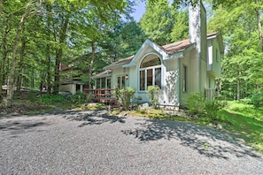 A rustic cabin with a gravel driveway, surrounded by dense forest. - Deck & Resort Amenities: Pocono Lake Home (Pocono Lake)