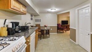 A kitchen with a gas stove, coffee maker, and a dining area with a table and chairs. - Seaside Heights Apt < 2 Blocks to Boardwalk! (Seaside Heights)