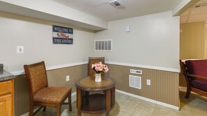 A kitchen with wooden cabinets, a dining table with chairs, a welcome sign, and a vent on the wall. - Seaside Heights Apt < 2 Blocks to Boardwalk! (Seaside Heights)