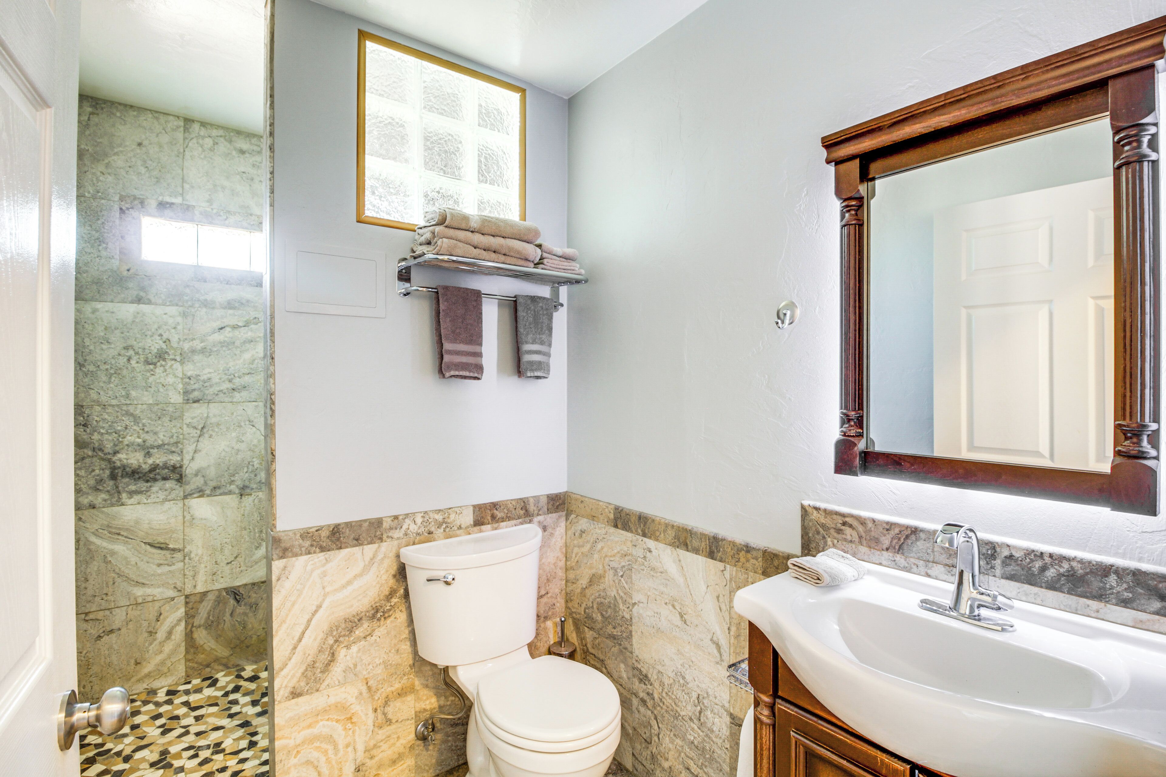 Un baño con inodoro, lavabo y espejo sobre el lavabo.
