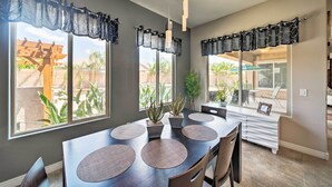 A dining area with a large table, multiple chairs, and a view of the outdoors through large windows. - Hot Tub & Putting Green: Home in Surprise (Surprise)