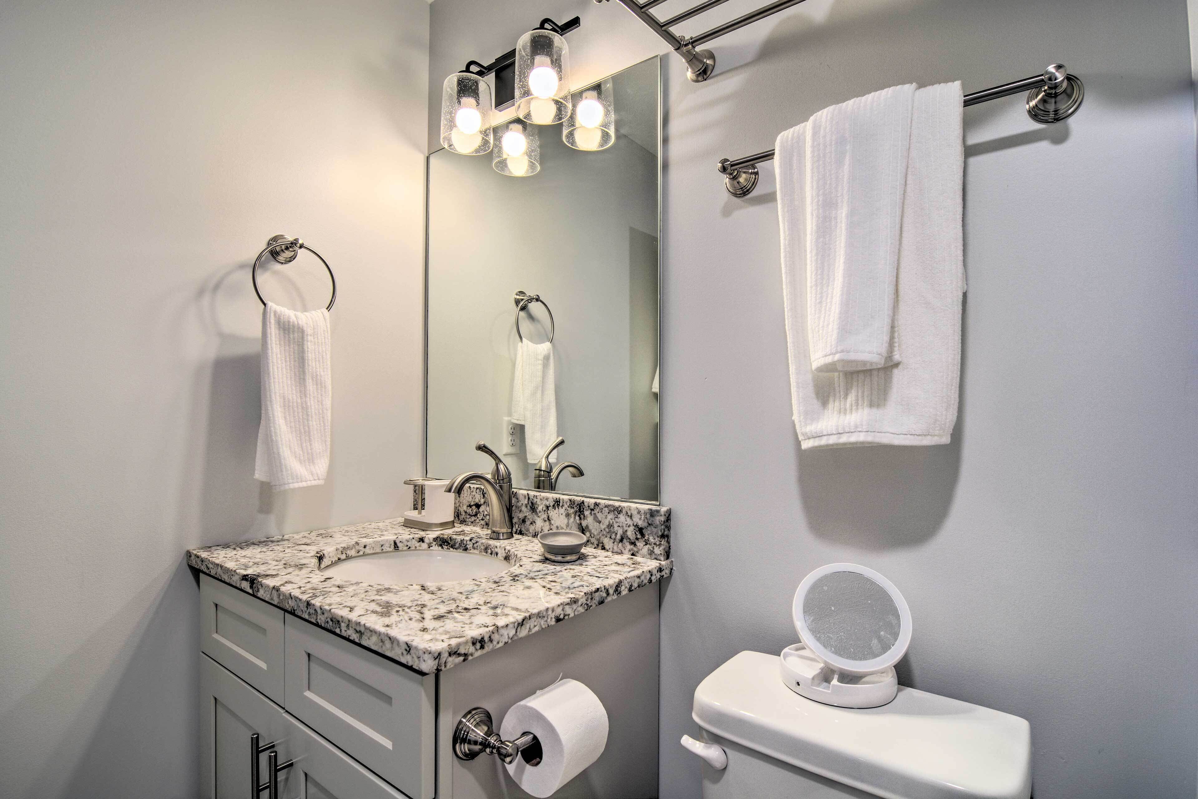 Ein Badezimmer mit Waschbecken, Spiegel, Handtuchhalter, Toilette und Seifenschale.