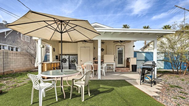Eine Terrasse mit Tisch und Stühlen, einem Grill und einem überdachten Bereich mit Waschmaschine.