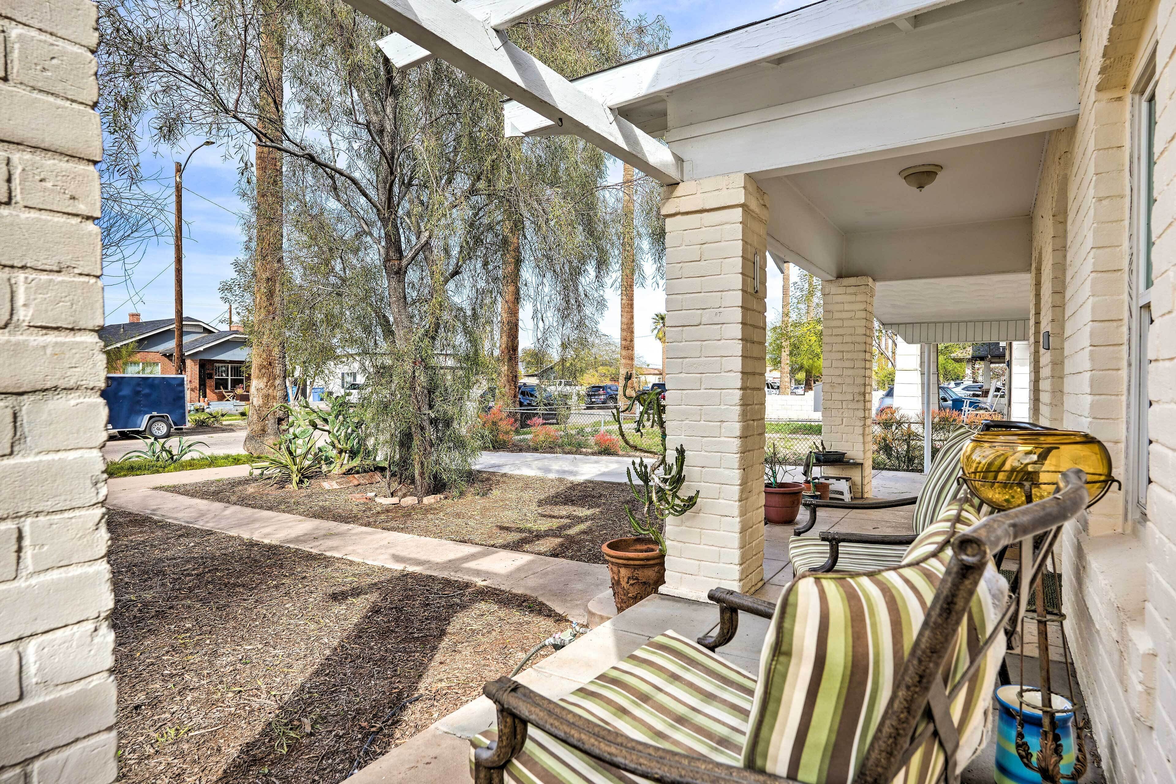 A covered outdoor seating area with striped chairs and a small tree.