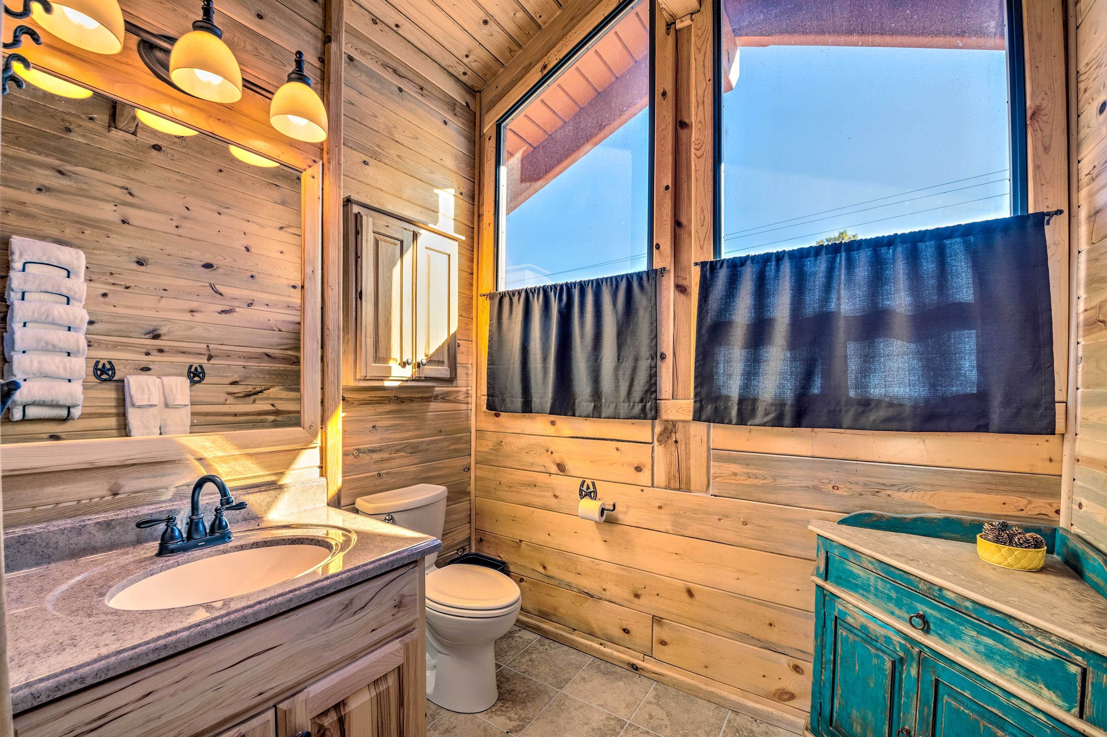 A wooden cabin bathroom with a sink, toilet, and mirror.