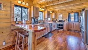 Une cuisine spacieuse avec des meubles en bois, un grand îlot central doté de tabourets, des appareils électroménagers en acier inoxydable et un éclairage suspendu.
