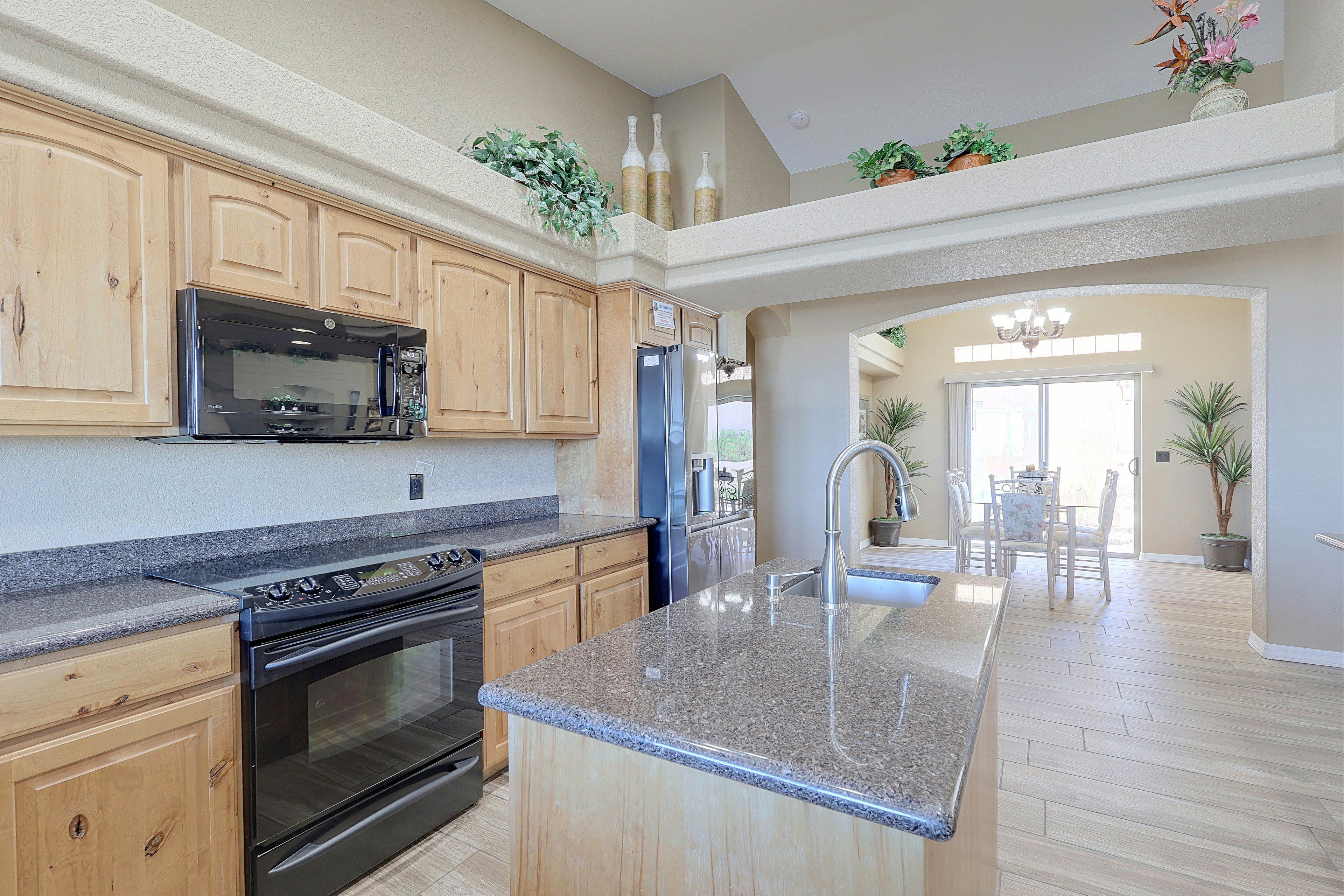 A kitchen with granite countertops, wooden cabinets, stainless steel appliances, and a central island.