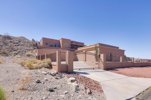Una casa moderna con ingresso chiuso da cancello, vialetto lastricato e paesaggio desertico.