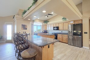 A spacious kitchen with a central island, wooden cabinets, stainless steel appliances, and a view to the outside. - Infinity Pool & Lake Views: Havasu Group Escape (Lake Havasu City)