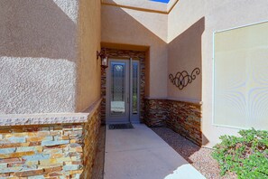 A building entrance with a stone facade, a glass door with a metal handle, and a small step leading to the entrance. - Infinity Pool & Lake Views: Havasu Group Escape (Lake Havasu City)