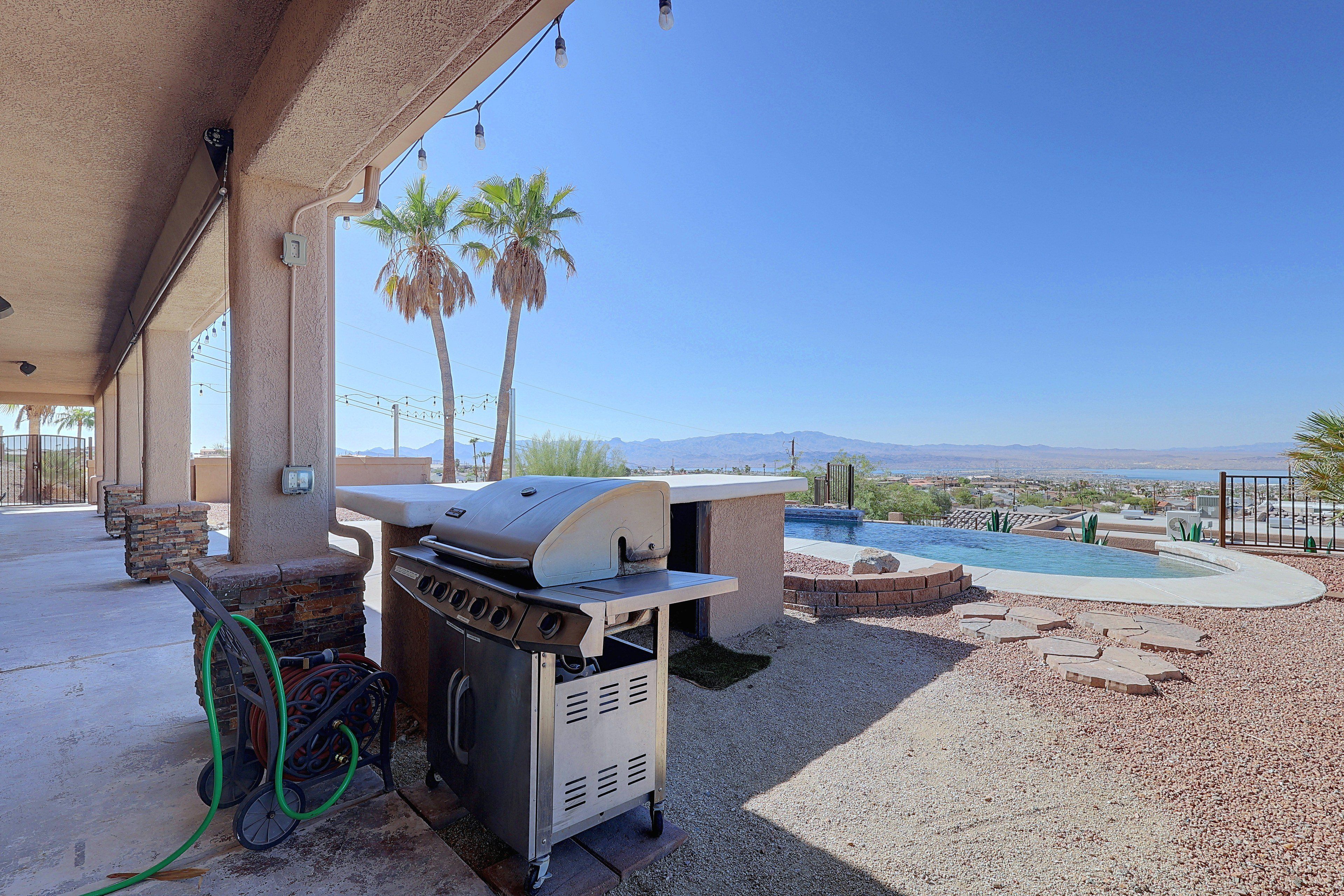 Eine Terrasse im Freien mit einem Grill, einem Pool und Blick auf die Berge.