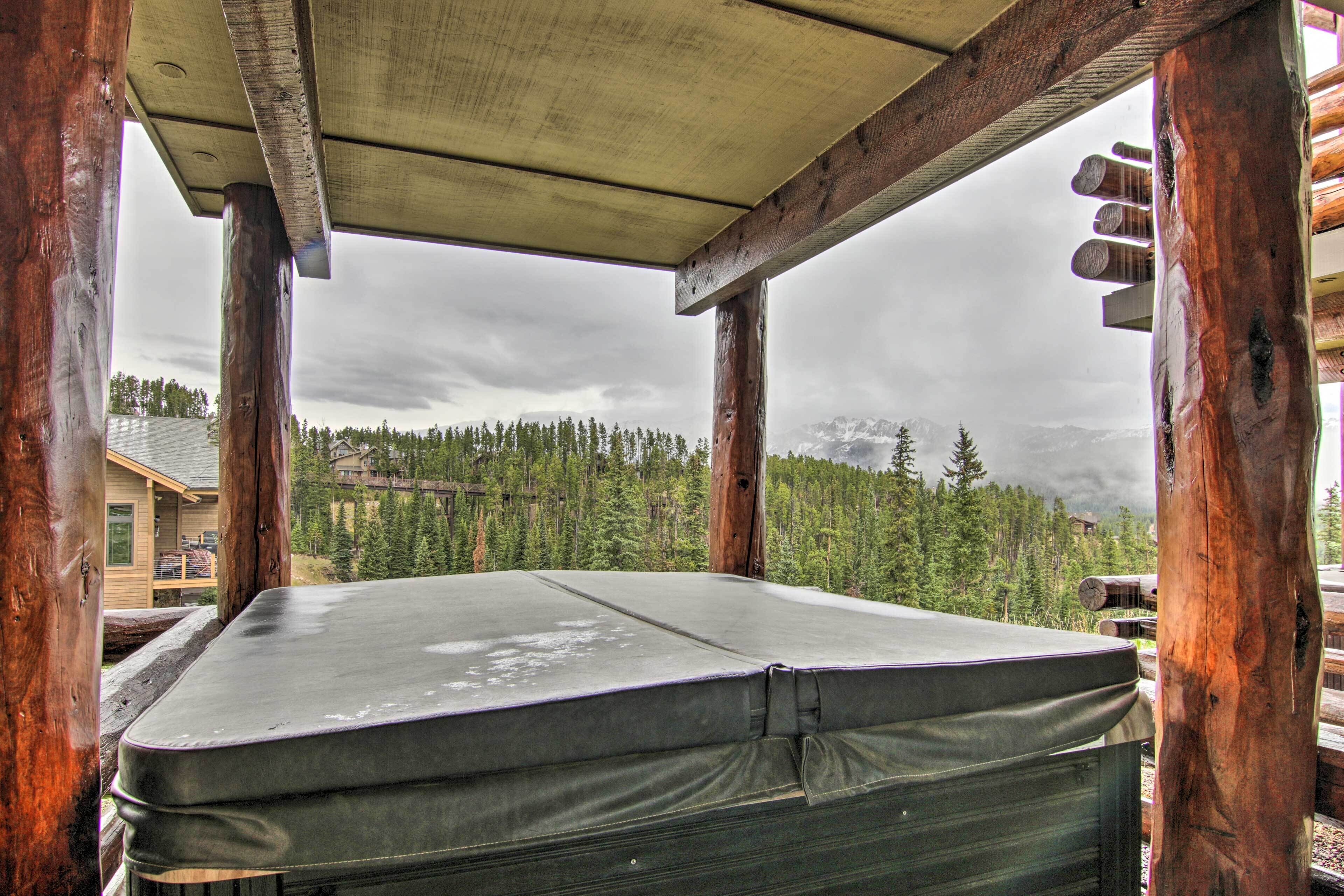 A wooden cabin with a mattress on the floor, surrounded by a forest and mountains.