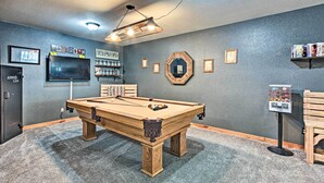 A pool table in a room with a grey wall, a mounted TV, and a vending machine. - La Pine Hideaway Near Deschutes National Forest! (La Pine)