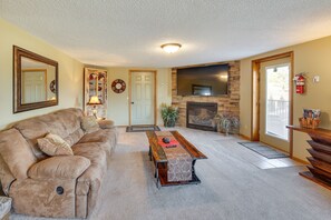 Relax in this inviting living room with a plush sofa, stone fireplace, and flat-screen TV.