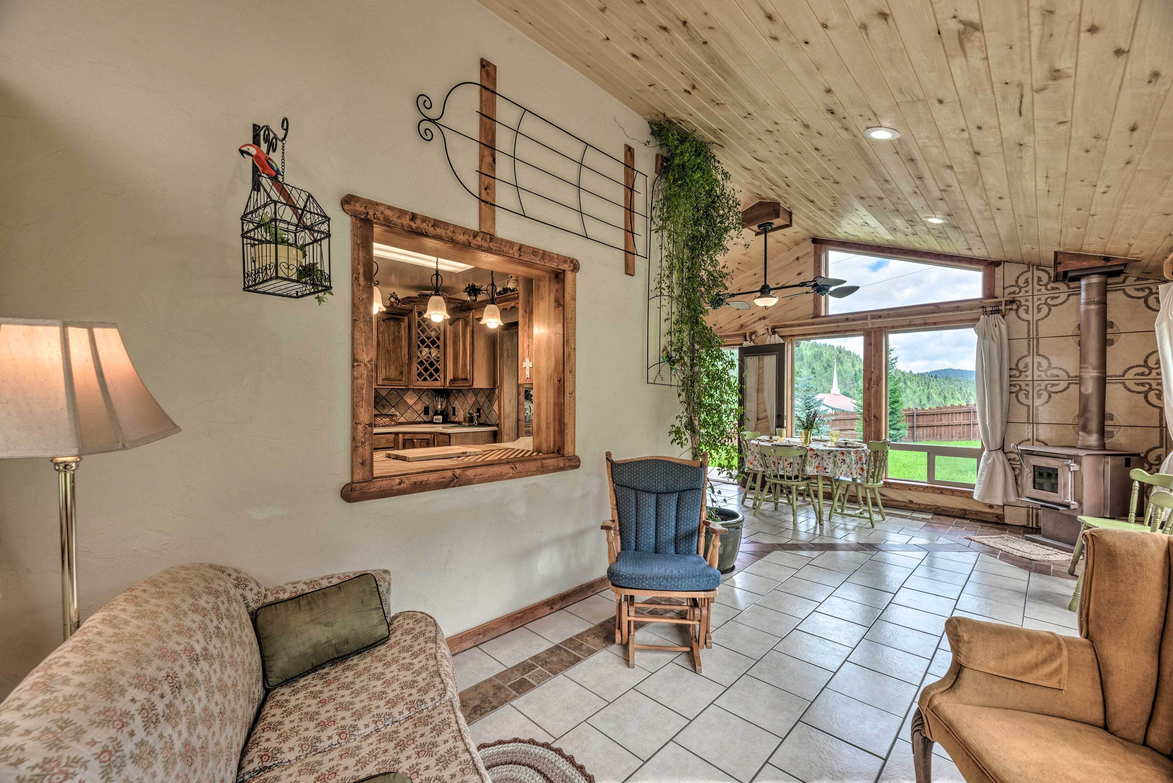A cozy living room with a wooden ceiling, a large window, and a fireplace.