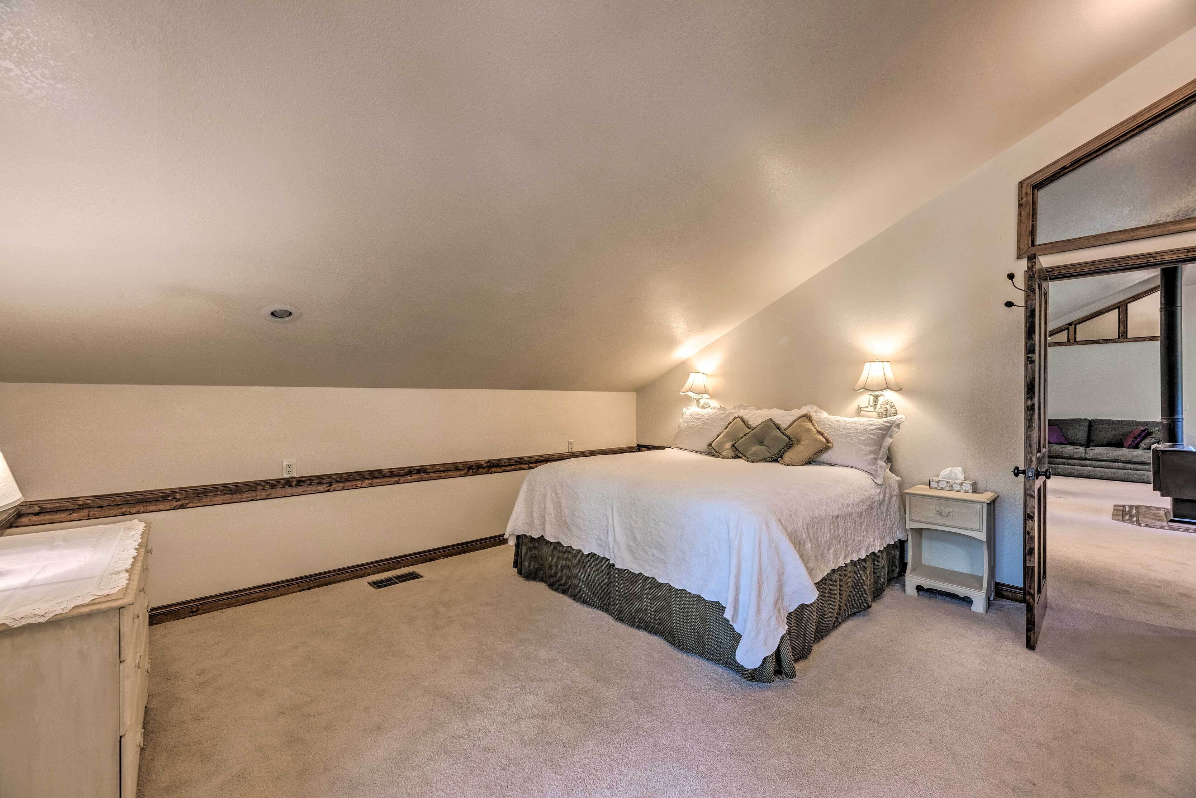 Une chambre à coucher avec un grand lit, une table de chevet, un miroir et une porte donnant sur une autre pièce.
