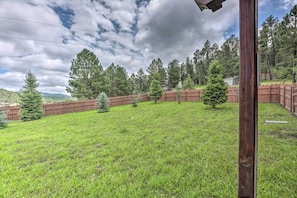 A grassy backyard with a wooden fence, trees, and a cloudy sky. - Valley Cloudcroft Hideaway < 8 Mi to Town! (Cloudcroft)