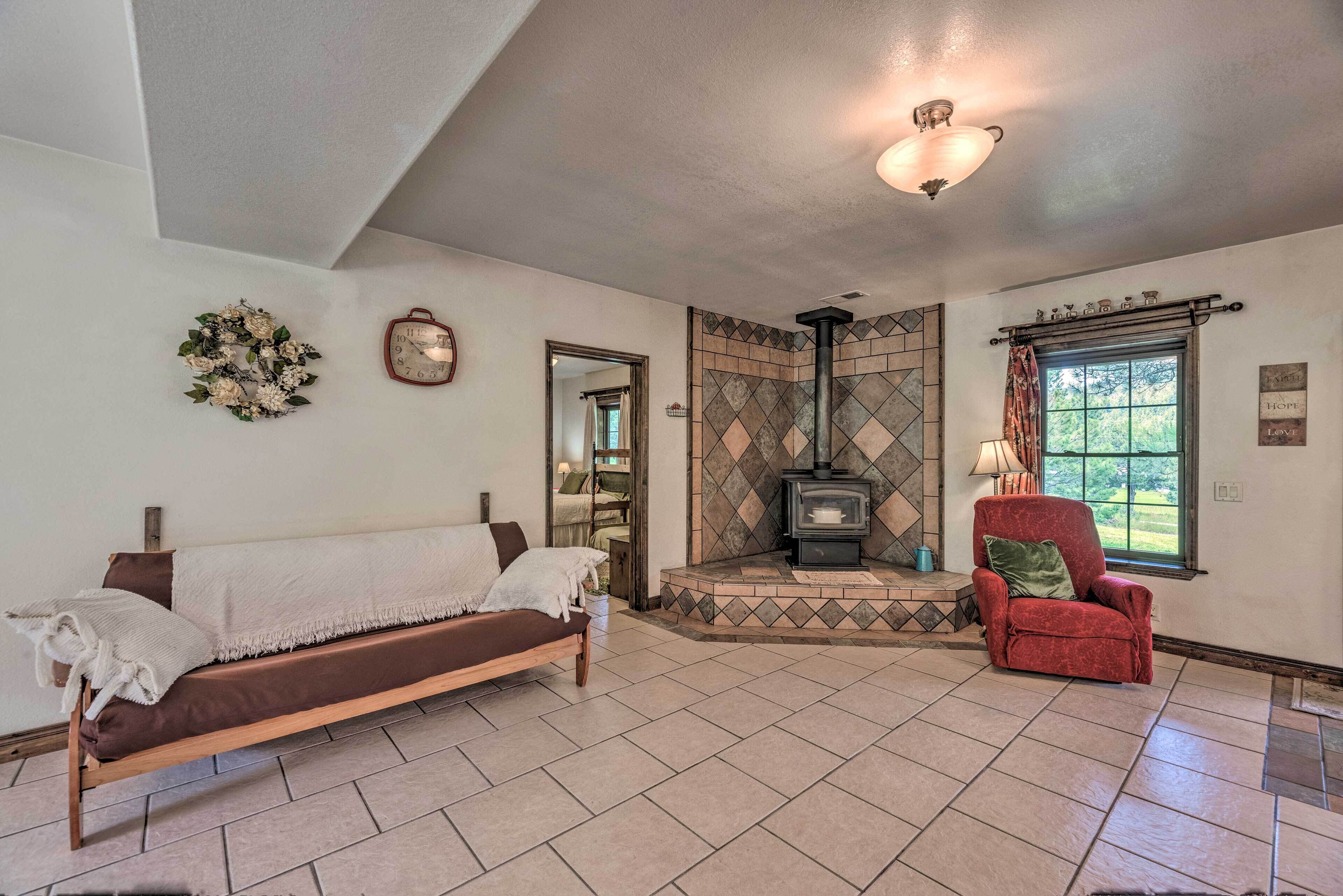 A cozy living room with a sofa, armchair, fireplace, and a view of the outdoors.