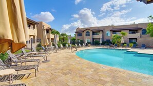 A pool area with lounge chairs and umbrellas, surrounded by buildings with a tiled roof. - Walkable Scottsdale Gem w/ Pool Access (Scottsdale)