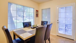 A dining area with a table and chairs, large windows, and a door with blinds. - Walkable Scottsdale Gem w/ Pool Access (Scottsdale)