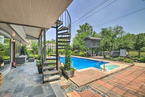 Un jardin avec une piscine, un escalier en colimaçon, du mobilier d’extérieur et une pergola.