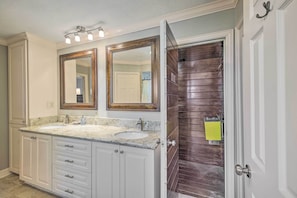 Une salle de bain avec deux lavabos, un grand miroir et une porte en bois.