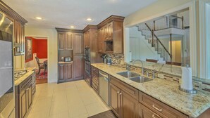 Una cucina moderna con piani di lavoro in granito, elettrodomestici in acciaio inossidabile e pensili in legno.