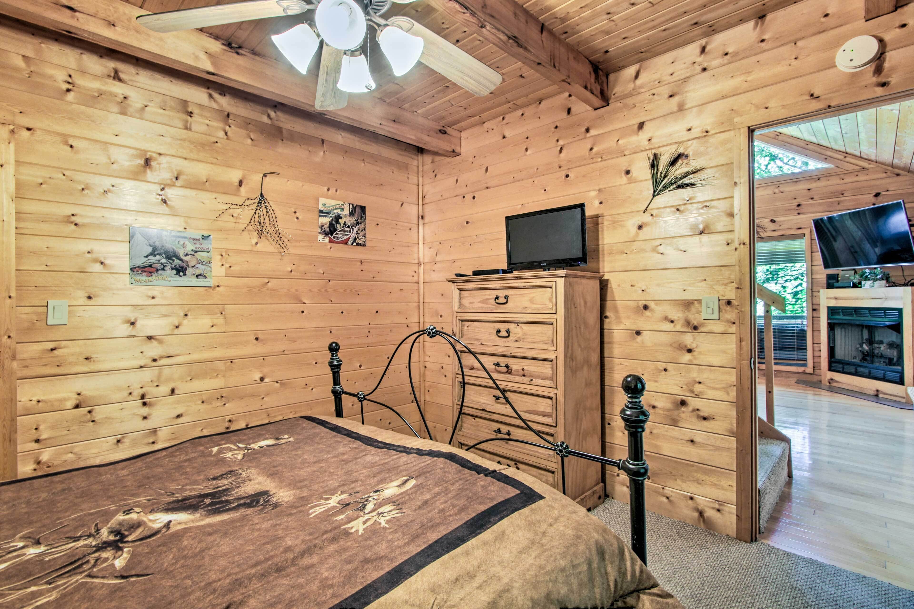 Een houten slaapkamer met een bed, een kapstok en een plafondventilator.