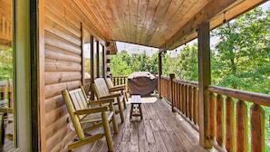A wooden deck with rocking chairs and a barbecue grill. - Cabin w/ Hot Tub & Deck ~ 12 Mi to Pigeon Forge! (Sevierville)