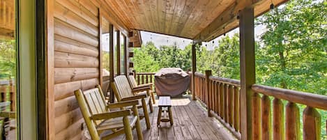 A wooden deck with rocking chairs and a barbecue grill.