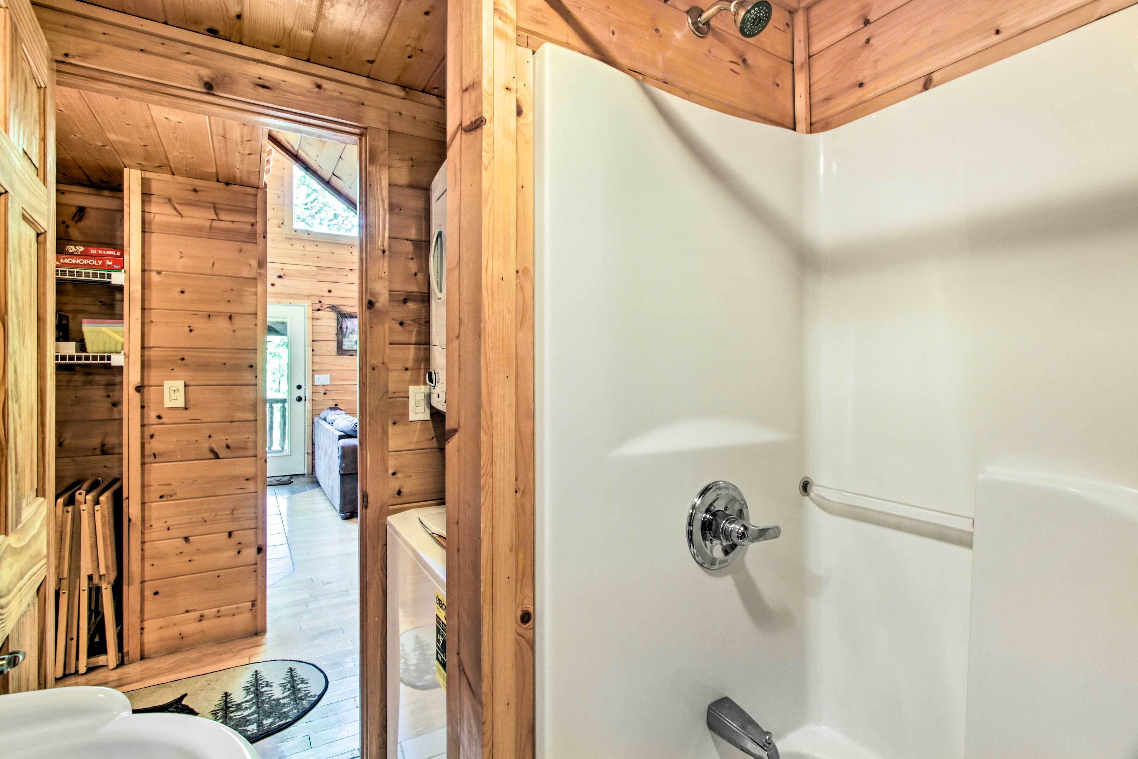 A wooden cabin interior with a white bathtub, wooden walls, and a visible door leading to another room.