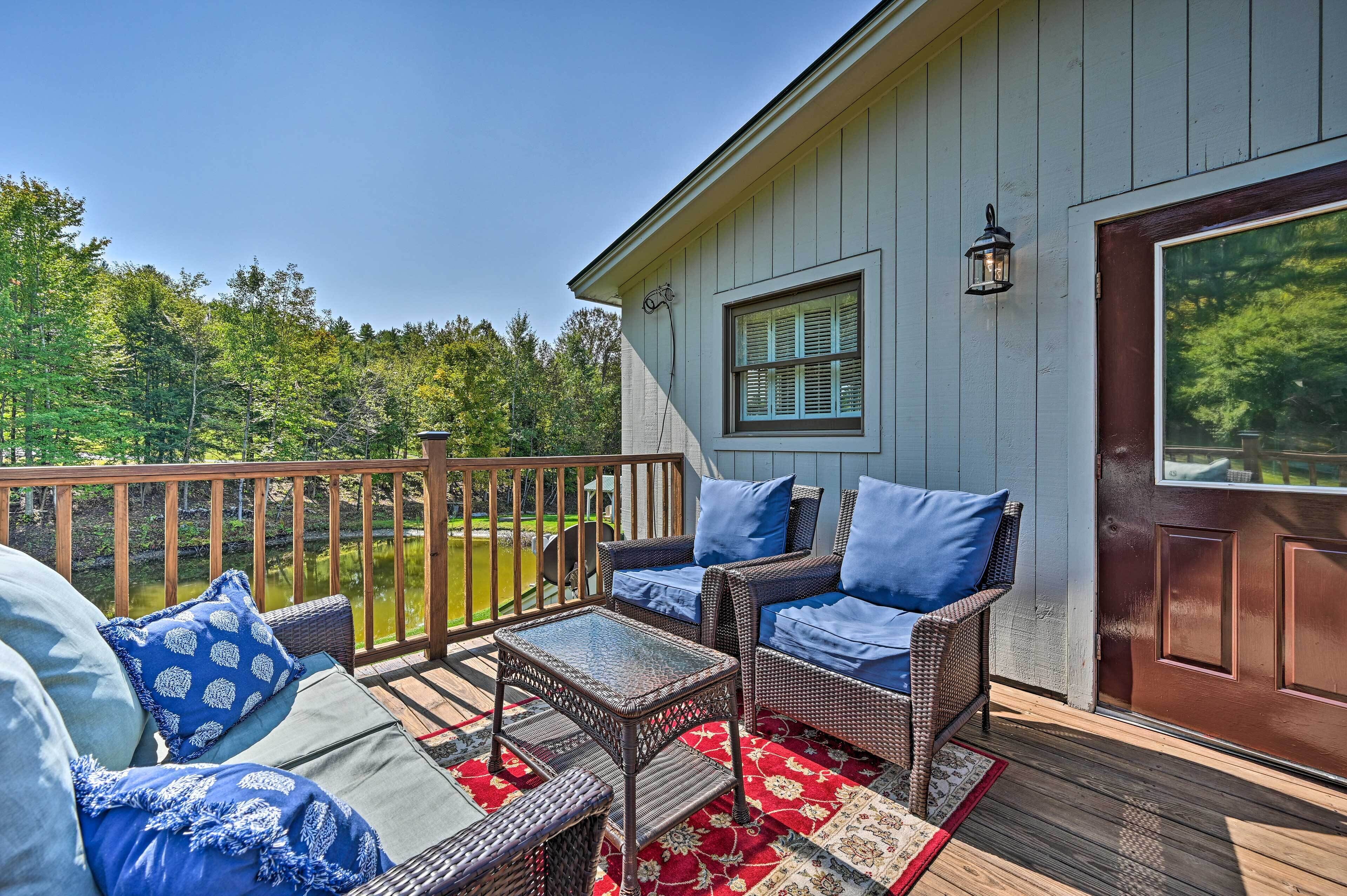 A deck with wicker furniture and a red and white patterned rug.
