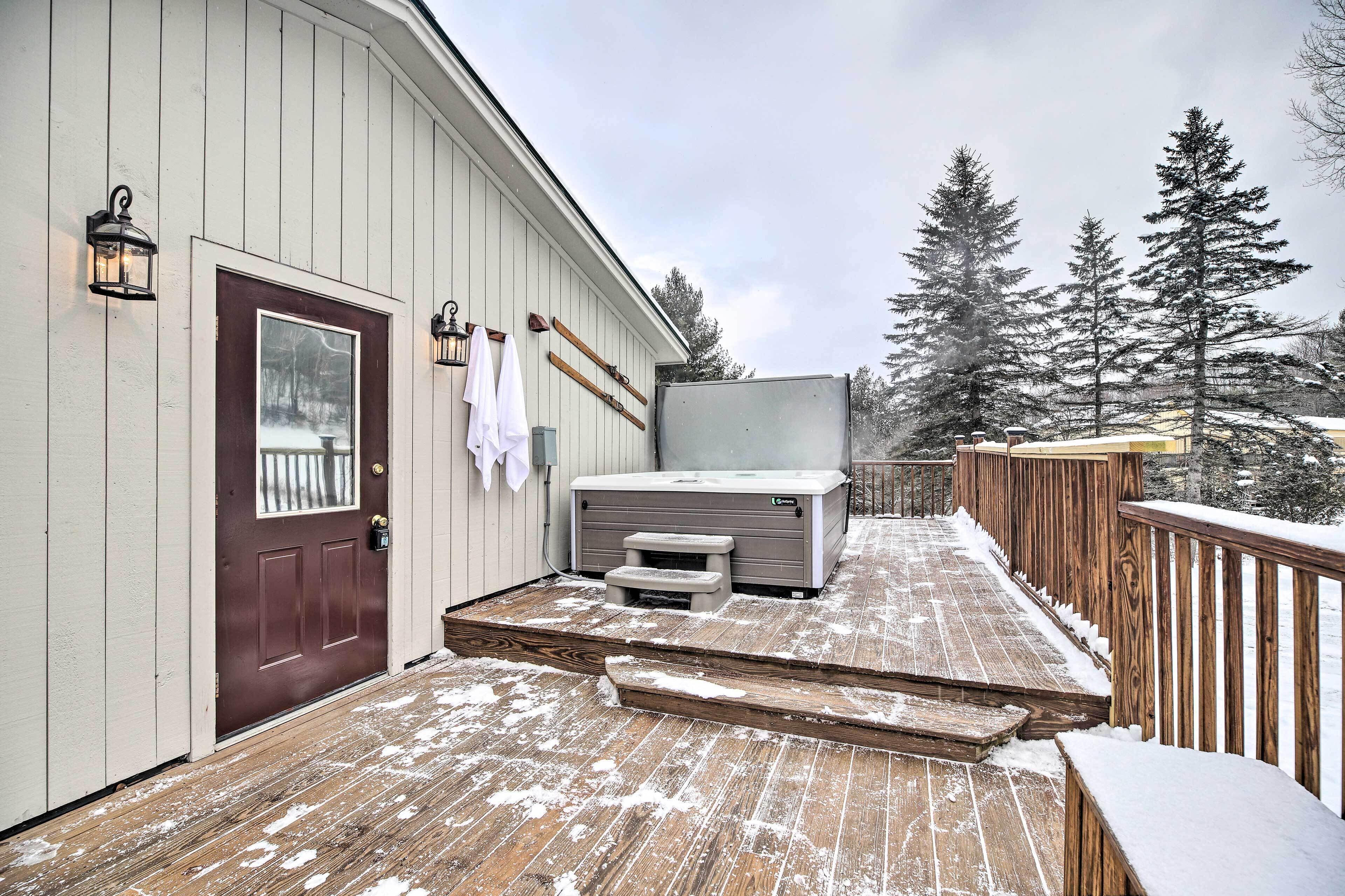 Eine Holzterrasse mit Sauna, einer Holztür und einem Geländer.