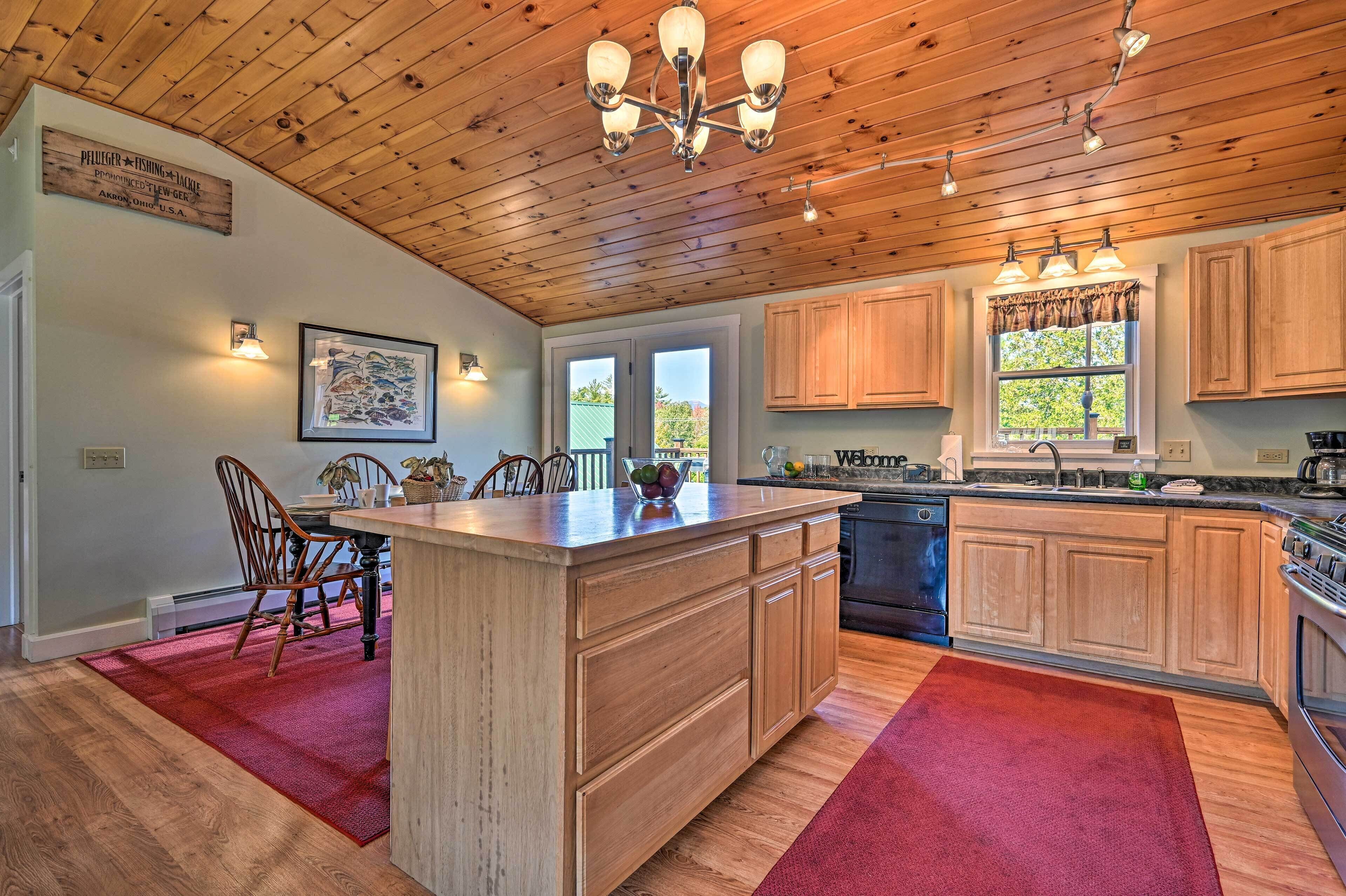 A spacious kitchen with wooden cabinets, a central island, and a dining area with chairs.