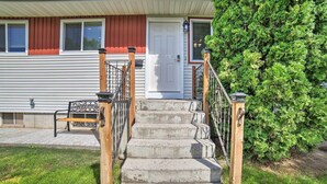 Une maison d’habitation avec un porche à l’avant, un escalier en bois et une pelouse bien entretenue.
