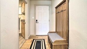 Un couloir avec un banc en bois, une porte blanche et des armoires en bois.