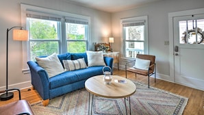 A living room with a blue sofa, a round wooden coffee table, and a patterned rug.