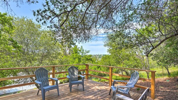A wooden deck with Adirondack chairs and a view of a lake.