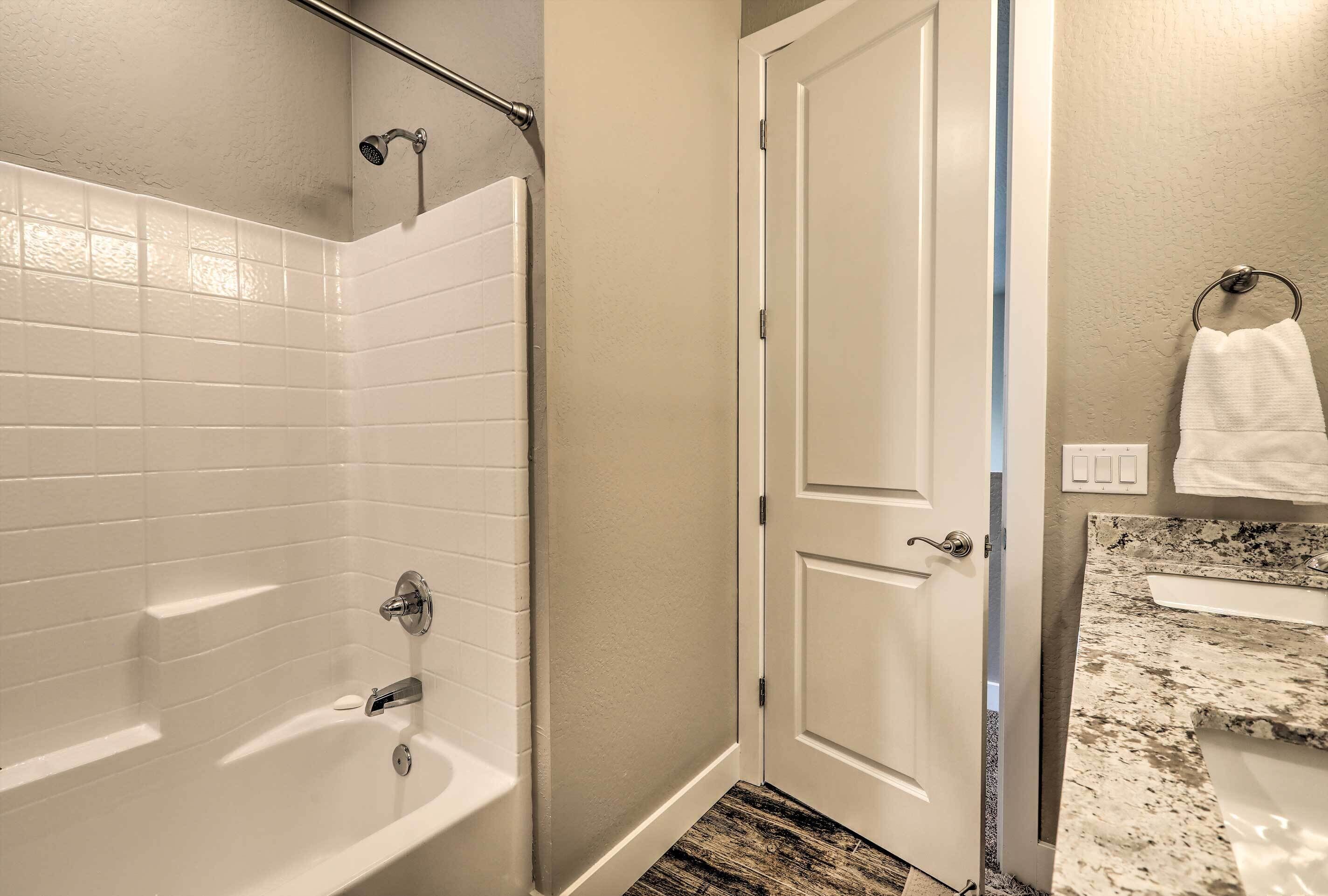 Un bagno con vasca, doccia e una porta che dà su un'altra stanza.