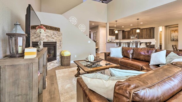 A spacious living room with a fireplace, leather sofas, and a dining area with a kitchen in the background. - Family Home w/ Deck, 3 Mi to Downtown Flagstaff! (Flagstaff)