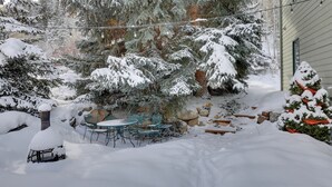 A snow-covered outdoor area with a patio table and chairs, surrounded by snow-laden trees and a house. - Eclectic Eagle-vail Condo: 2 Miles to Beaver Creek (Avon)